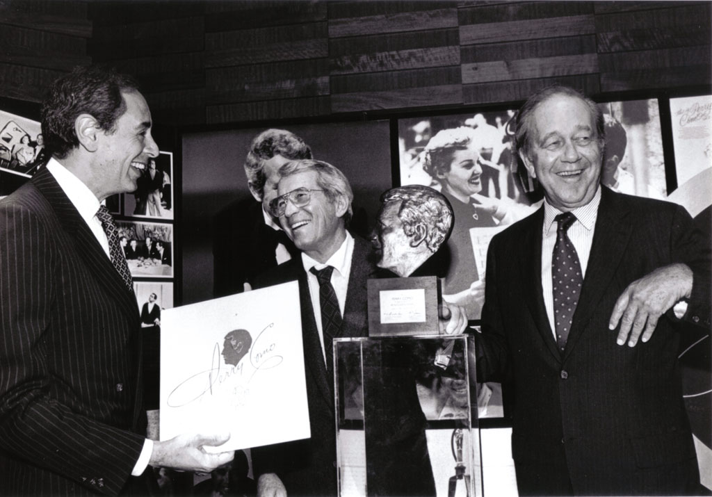 Shown at RCA's salute to Perry Como on his 40th anniversary with RCA Records and 50th anniversary in show business are Robert D. Summer, President of RCA Records (left), Como and Thornton F. Bradshaw, Chairman and Chief Executive Officer of RCA Corporation. Summer is holding a special non-commercial album containing some of Perry's favorite songs given to guests. The bronze silhouette of Perry's face, presented to the artist, is at Perry's right. The reception was held at the Rainbow Grill of New York's Rockefeller Center. It was announced to the guests that Como and his wife, Roselle, who also attended, will celebrate their 50th wedding anniversary on July 31.